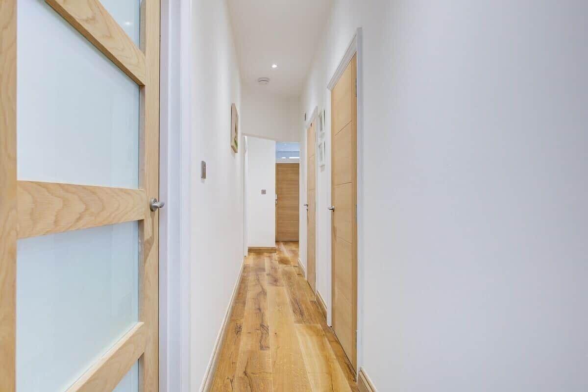 A hallway with wooden doors, white walls, and a wooden floor.