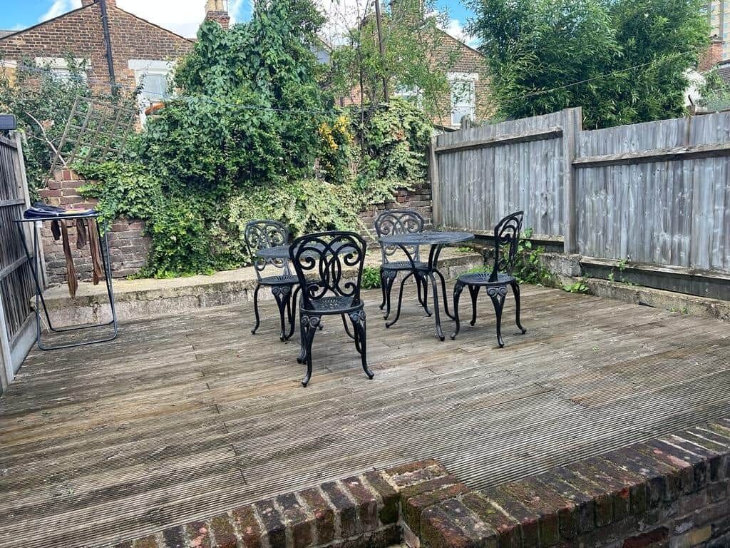 Un patio al aire libre con cubierta de madera, una mesa de metal y sillas.