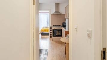 A hallway leading to a kitchen with a stove, oven, and cabinets.