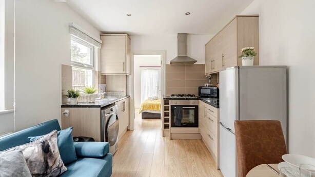 A compact kitchen with a dining area, a sofa, and a chair. - Springfield - The Earl (London)