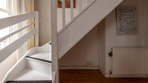 Un escalier avec des rampes blanches mène à un palier. Un panneau sur le mur affiche une liste de divers mots liés aux fruits de mer et à la détente.