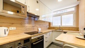 Eine kompakte Küche mit Geschirrspüler, Backofen und einem Fenster mit Jalousien.