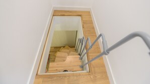 Eine Holztreppe mit Metallgeländer, die zu einem Erker führt.