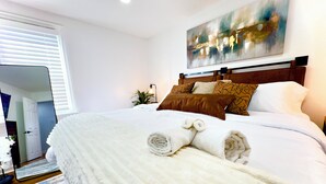 Una cama bien hecha con toallas enrolladas, un cabecero de madera y un cuadro encima.