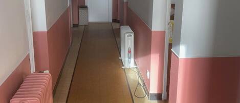 A hallway with a radiator, a heater, and a door marked "WC".