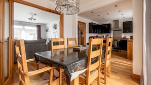 Ein Essbereich mit Tisch und Stühlen, einer Deckenleuchte und einer Küche im Hintergrund.