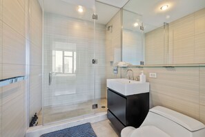 A modern bathroom with a glass-enclosed shower, a white sink with a black cabinet, and a large mirror. - 2 bedroom luxury Empire State VIEW (New York)