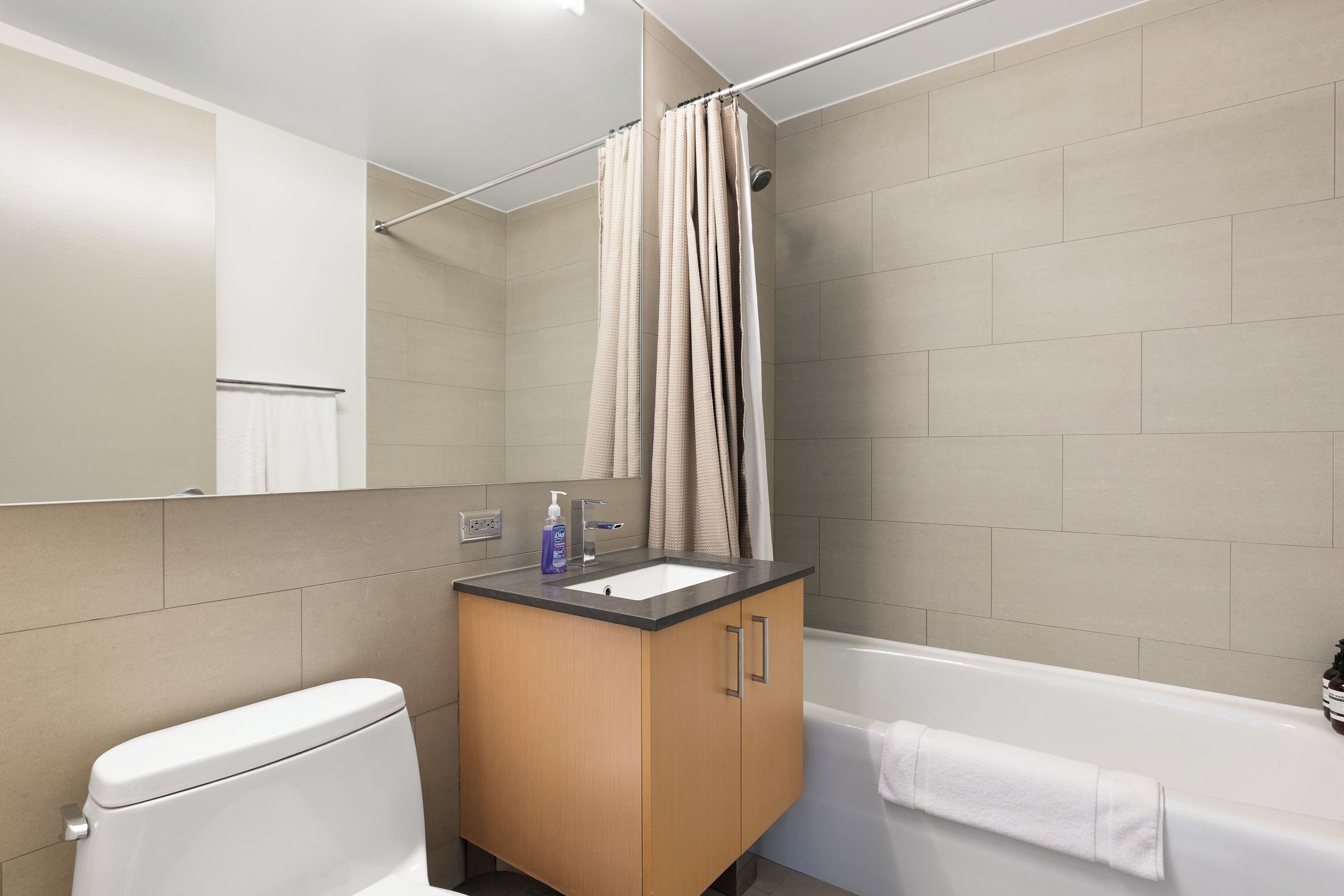 A bathroom with a toilet, sink, cabinet, shower curtain, and bathtub.