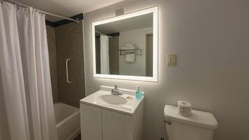 A bathroom with a shower, a sink, a toilet, and a mirror.