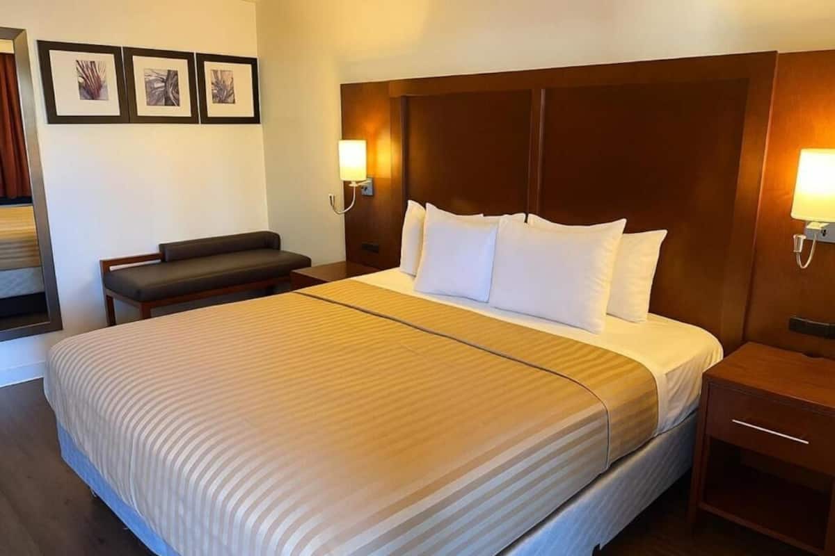 Ein Hotelzimmer mit einem großen Bett, einem Nachttisch, einer Bank und Wandlampen.