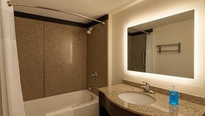 Une salle de bain avec une baignoire, un lavabo et un grand miroir.