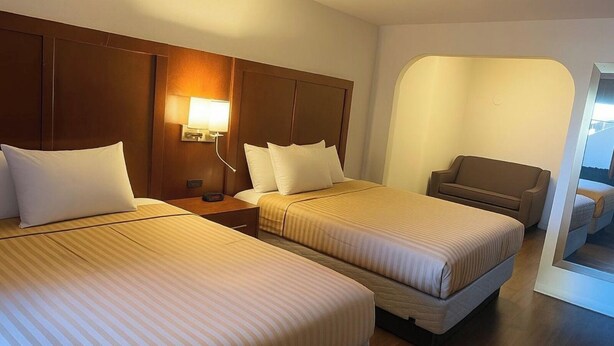 Une chambre d’hôtel avec deux lits, un canapé, une lampe et une vue sur la mer.