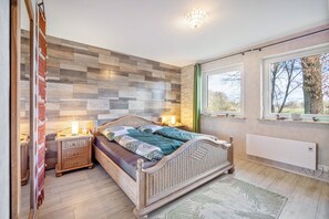 Makuuhuoneessa on puinen pääty, kuviollinen vuodevaatteilla varustettu sänky, yöpöytä lampun kanssa, patteri ja ikkuna, josta avautuu näkymä puihin.