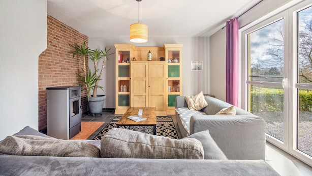 A modern living room with a sofa, a coffee table, a fireplace, and a large window. - Holiday Home 'Wohnung Wald' with Private Terrace, Garden and Wi-Fi (Ehndorf)