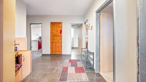 A hallway with a wooden door, a glass display case, and a patterned rug. - Holiday Home 'Wohnung Wald' with Private Terrace, Garden and Wi-Fi (Ehndorf)