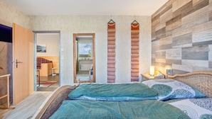 A bedroom with a bed, a wooden headboard, a nightstand, and a wall-mounted shelf. - Holiday Home 'Wohnung Wald' with Private Terrace, Garden and Wi-Fi (Ehndorf)