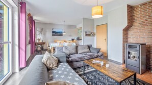 A modern living room with a sofa, coffee table, and a fireplace. - Holiday Home 'Wohnung Wald' with Private Terrace, Garden and Wi-Fi (Ehndorf)