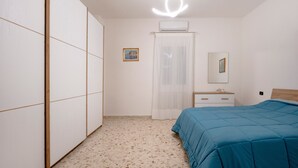 Une chambre à coucher comprenant un lit, une armoire, une table de chevet, un miroir et un luminaire au plafond.