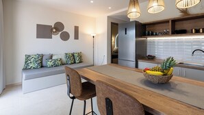 Una cocina moderna con una isla de madera, un refrigerador empotrado y una zona de comedor con banco y sillas.
