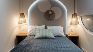 Un dormitorio moderno con una cama grande, dos mesitas de noche, un adorno circular en la pared y dos lámparas colgantes.