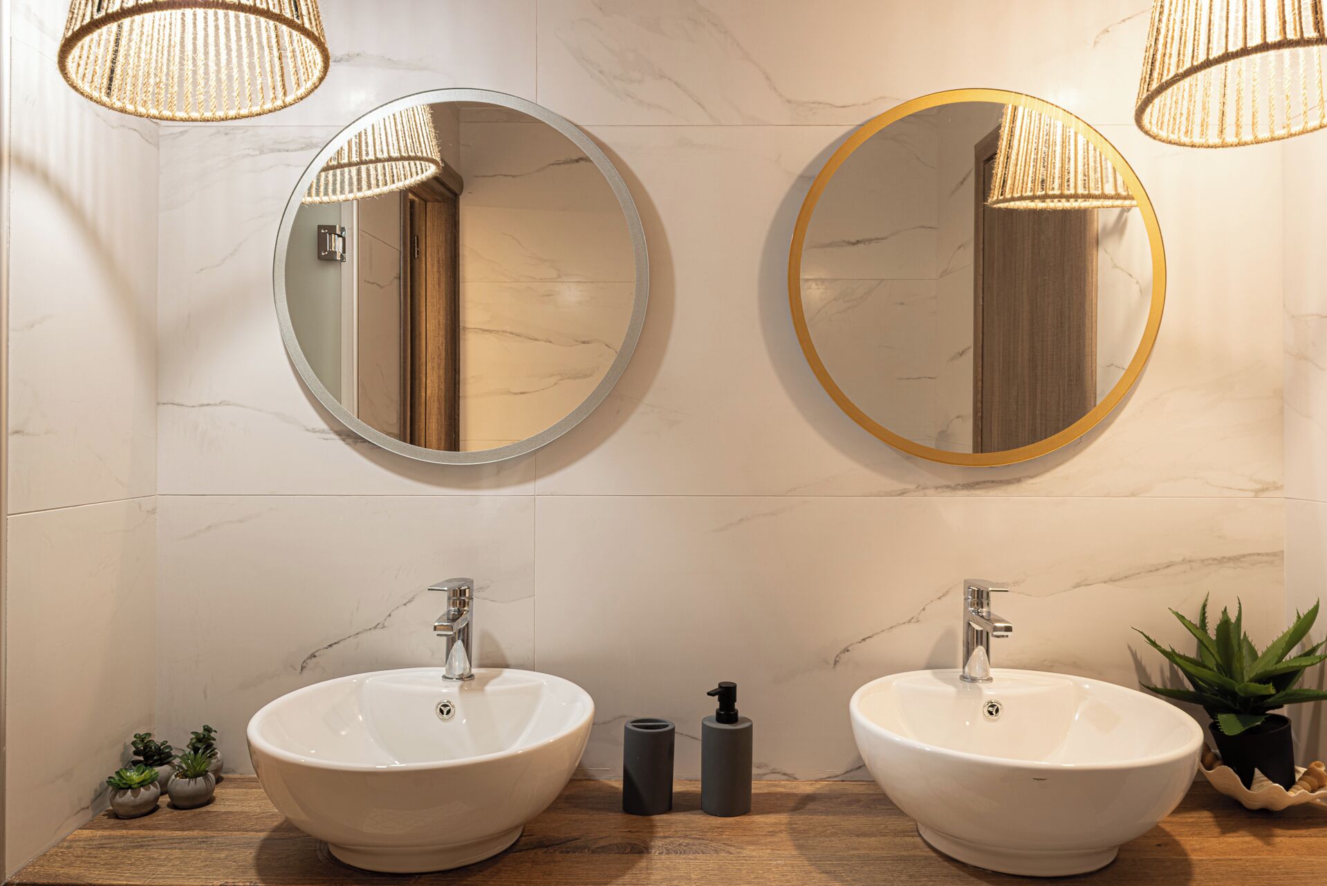 Een badkamer met twee ronde spiegels, twee wasbakken en een houten wastafelmeubel.