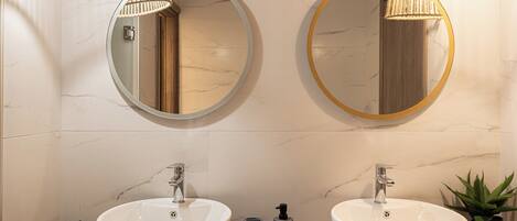 Een badkamer met twee ronde spiegels, twee wasbakken en een houten wastafelmeubel.
