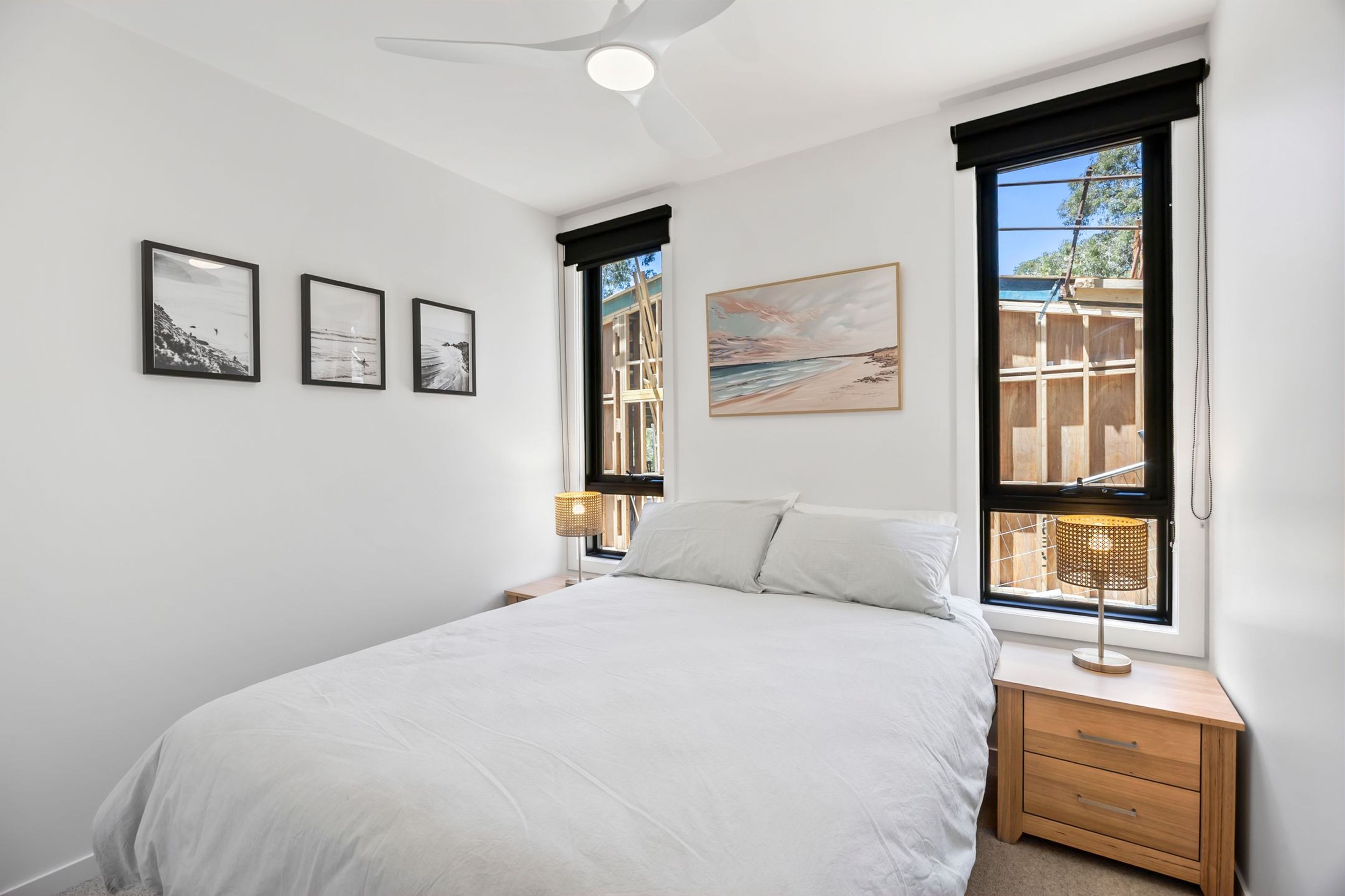A bedroom with a bed, a nightstand, a lamp, and a window with a view of a building.