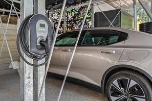 Ein Auto wird an einer Ladestation aufgeladen, mit einem digitalen Display und einem angeschlossenen Kabel.