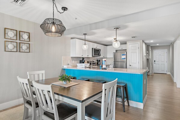 Una cucina moderna con mobili bianchi, un'isola blu e illuminazione a sospensione.