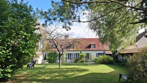 Ein gepflegter Garten mit einer Terrassenfläche, einem Esstisch und Stühlen.