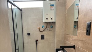 Ein modernes Badezimmer mit Duschkabine aus Glas, Toilette, Waschbecken mit schwarzer Arbeitsplatte und Spiegel.