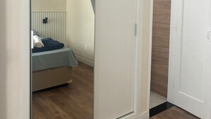 Ein Zimmer mit Schiebetürenschrank, einem Bett mit blauer Decke und Holzboden.