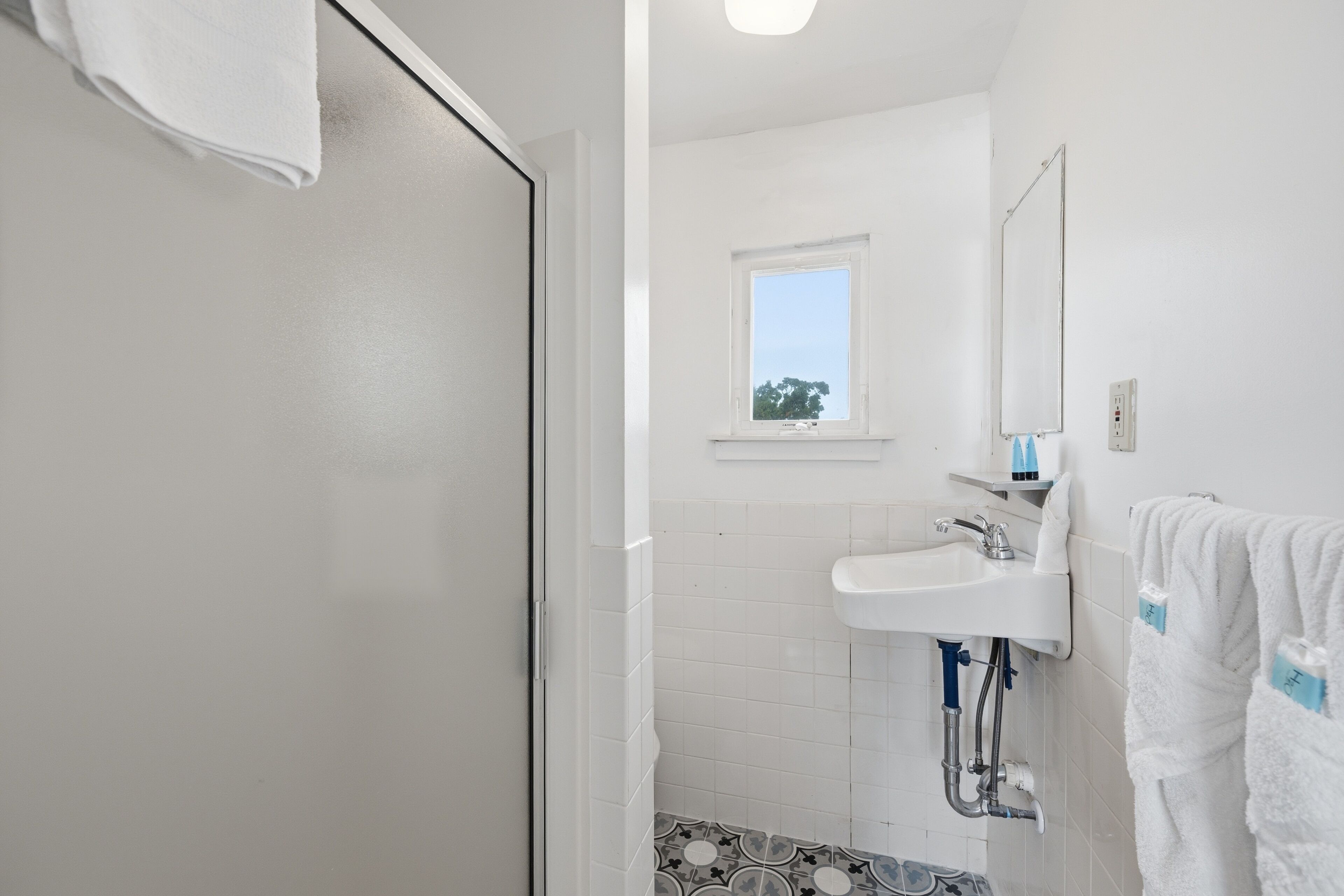 A bathroom with a white sink, a window, and a towel rack.