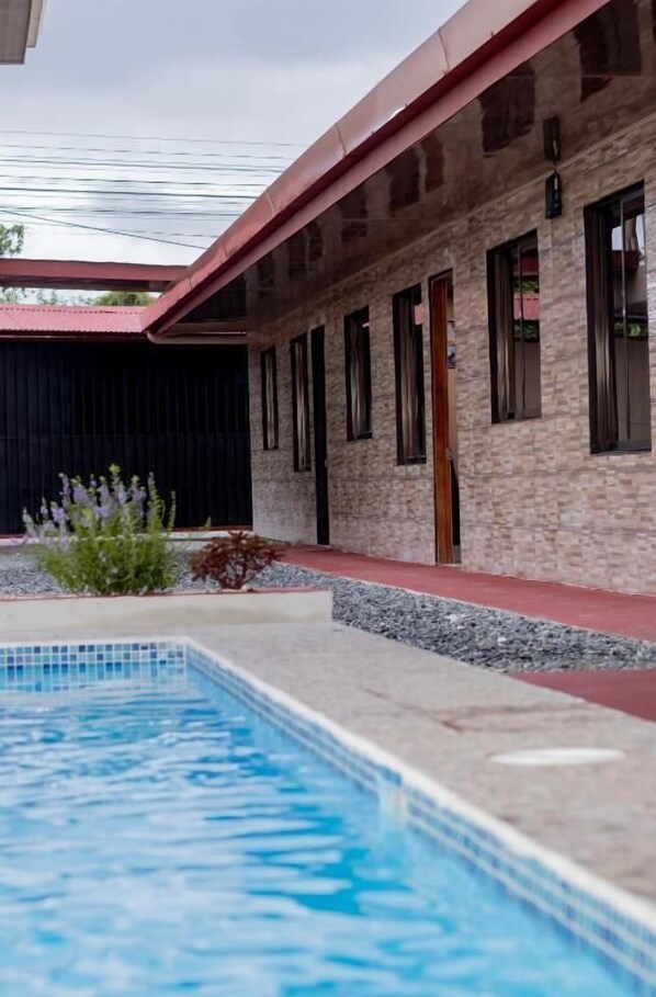 A swimming pool with a stone wall and a red roof.