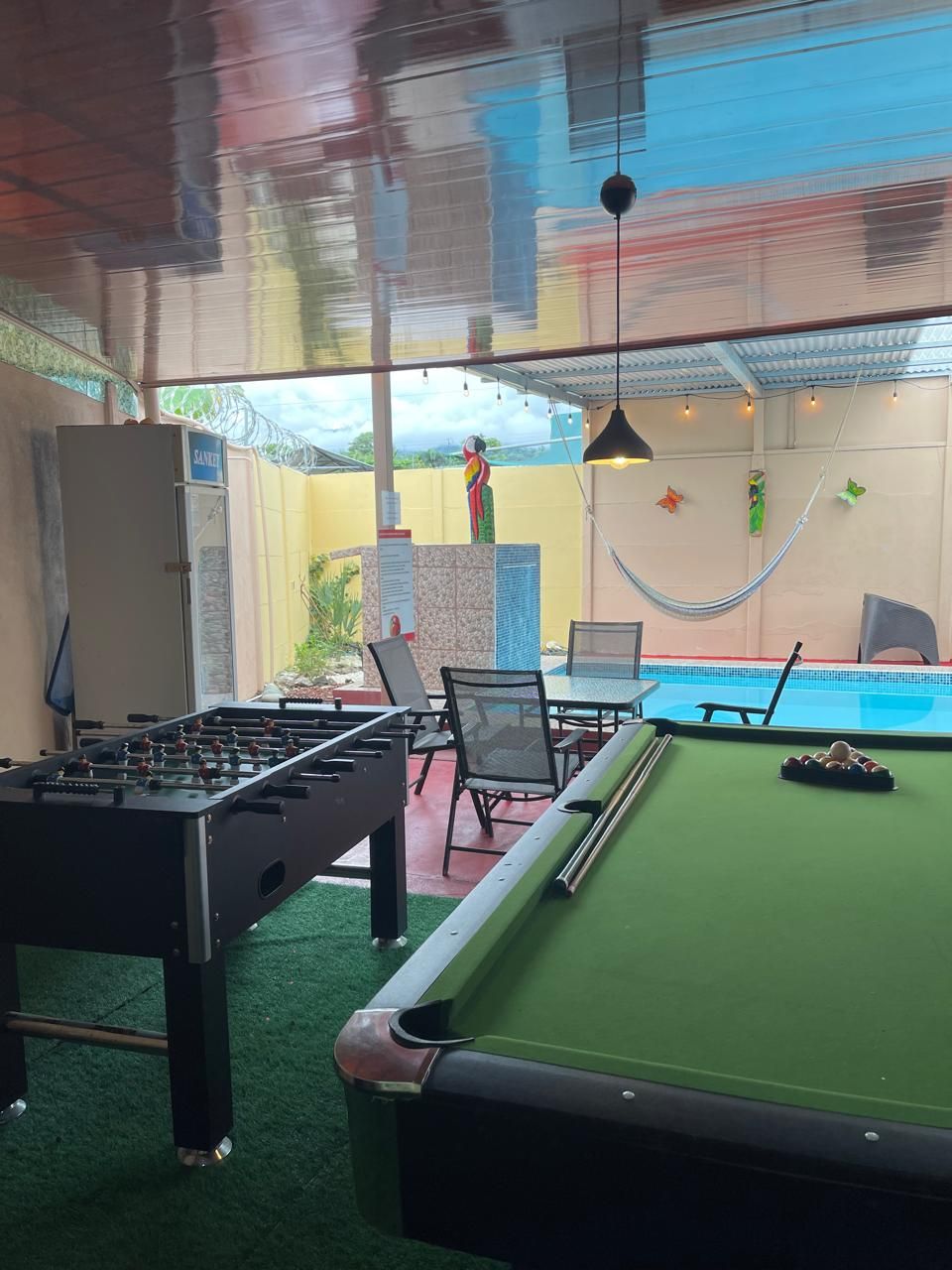 A pool table with a green felt surface, a foosball table, and a hammock.