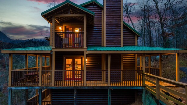 A two-story log cabin with a balcony and a covered porch. - Hold My Bear (Pigeon Forge)