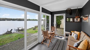 A room with a large sliding glass door leading to a deck with a view of a lake. - Peaceful Cable Lake Getaway w/ Dock & Views (Dowagiac)
