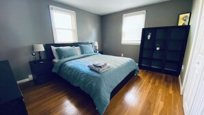 Une chambre à coucher comprenant un lit, des tables de chevet, une commode et un dressing.