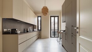 Una cocina moderna con armarios de tonos claros, una lámpara colgante y vistas al exterior a través de un ventanal.