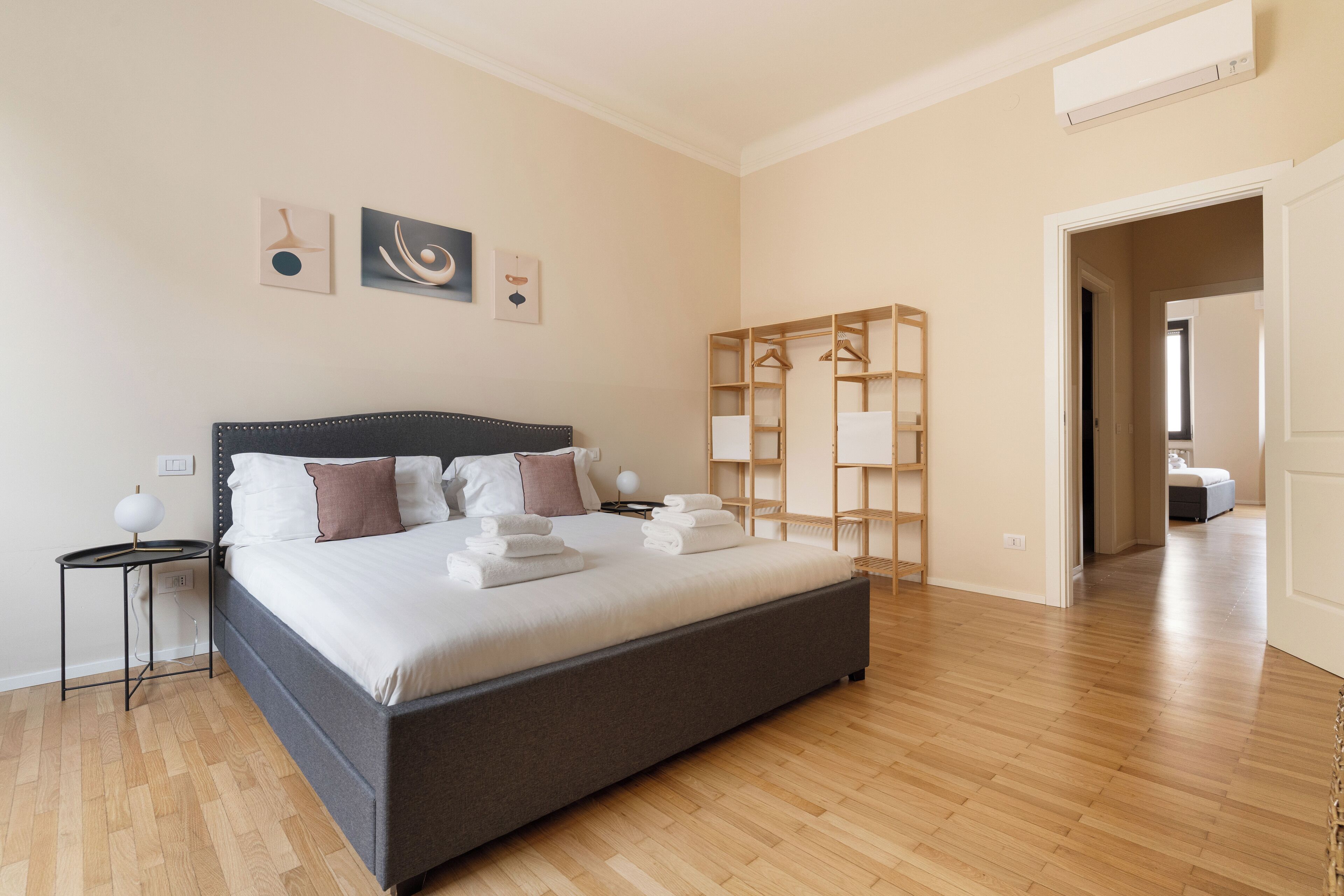 Un dormitorio moderno con una cama grande, una mesita de noche, un armario y un vestidor.