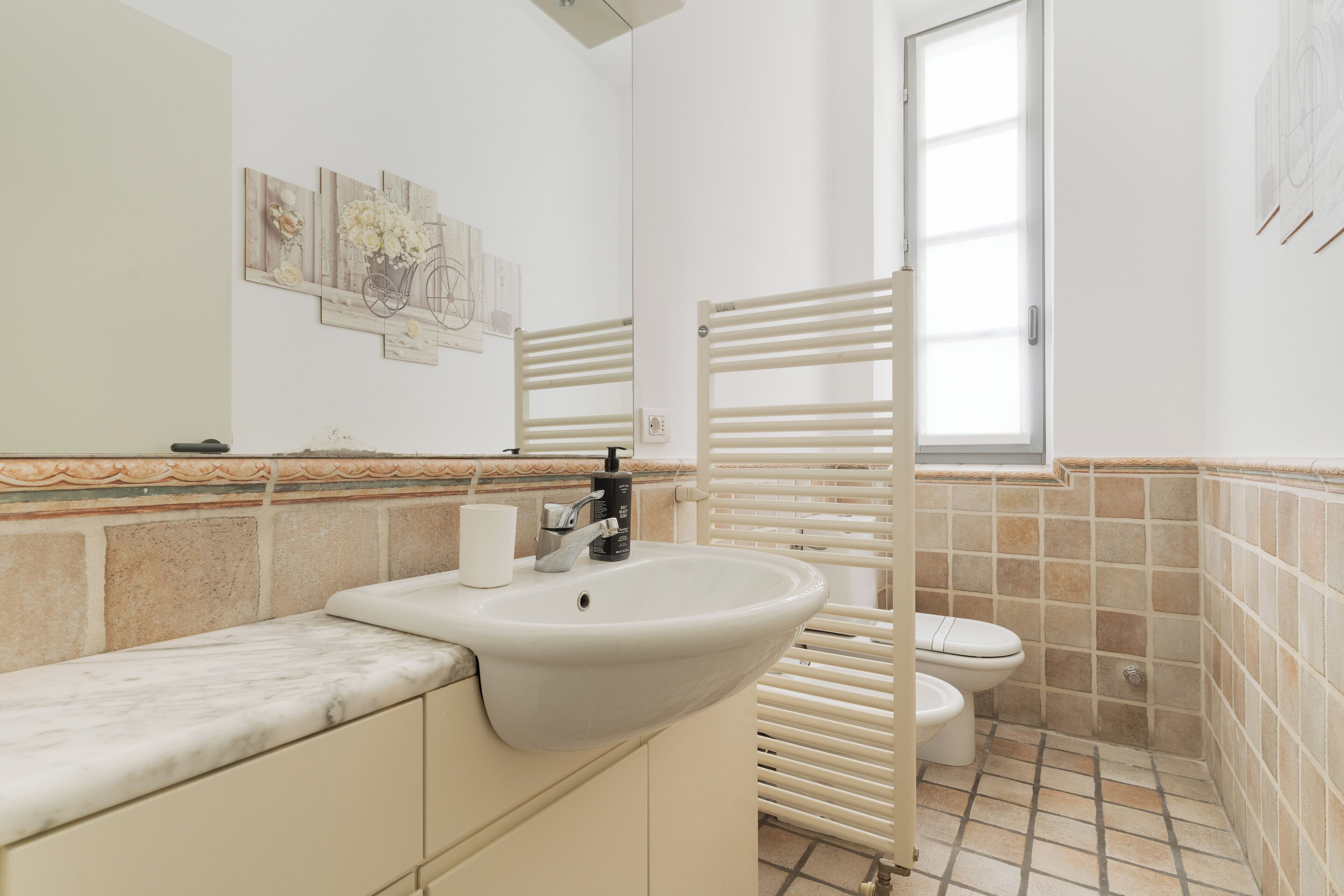 Un baño con lavamanos, inodoro y toallero.