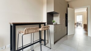 Una cocina moderna con dos taburetes de bar, una estufa empotrada y un comedor con mesa y sillas.