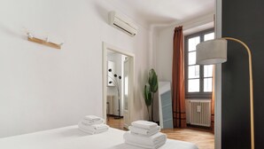 Habitación de hotel moderna con cama, espejo, equipo de aire acondicionado, planta y vistas al exterior.
