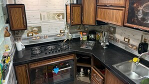 Eine Küche mit Holzschränken, einer schwarzen Arbeitsplatte, einer Edelstahlspüle und einem eingebauten Backofen.