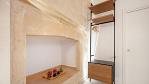 Una habitación con un estante de madera, una mesita con frascos y una puerta blanca.