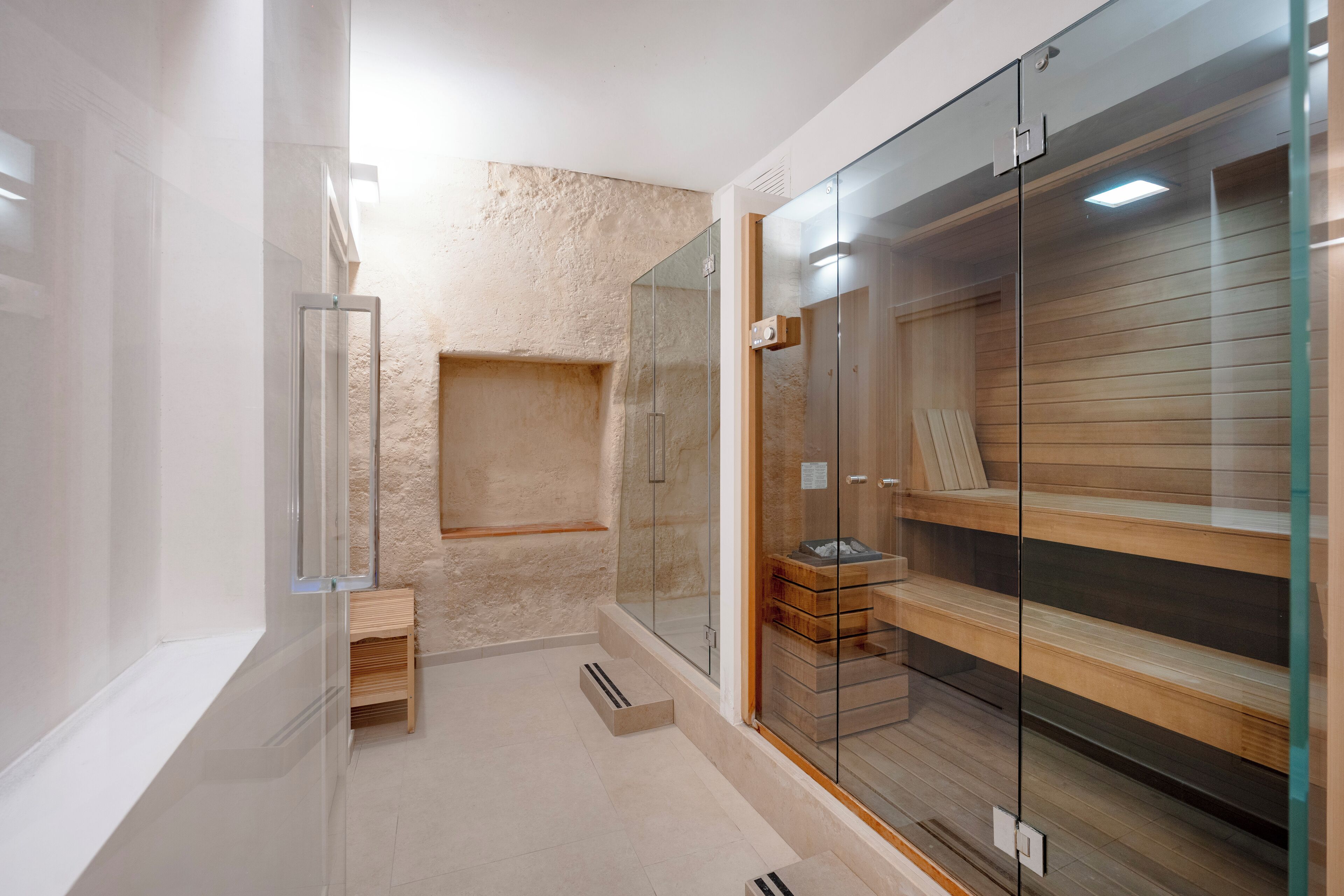 Ein modernes Badezimmer mit Duschkabine aus Glas, einer Holzbank und einer eingebauten Ablagefläche.