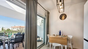 A balcony with a dining table, chairs, and a view of buildings. - Casa Louro in Cabanas (Tavira)