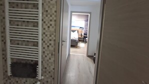 Un couloir avec un mur recouvert de carreaux et un radiateur blanc.