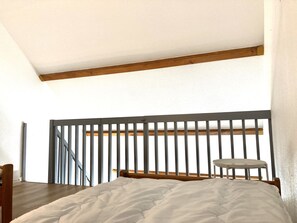 A bedroom with a bed, a small table, and a view of the outdoors. - 2 bedrooms with a mezzanine and south-facing doors (Le Lioran)