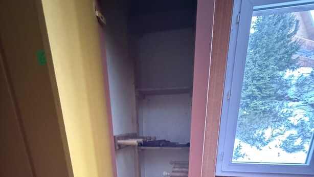 Kapea huone, jossa on ovi, ikkuna ja sininen, kuvioitu lattia.